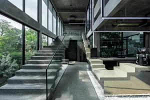 Open modern living area with natural light, multiple staircases, and concrete flooring