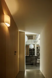 A well-lit room with wooden floors and walls, featuring a dining table, chairs, a couch, and a clock on the wall
