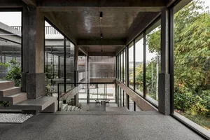 Open living space with a staircase, large windows, and potted plants, featuring a bright and inviting atmosphere