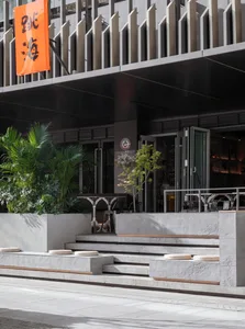 A calm exterior building facade with a staircase, two benches, and a potted plant, inviting a sense of relaxation