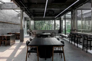 A spacious restaurant interior with a large dining table and comfortable seating, well lit with natural light from windows