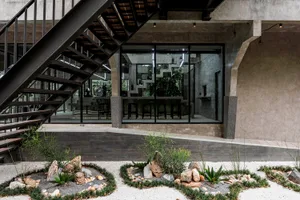 A modern living space with a staircase leading to a second floor, featuring chairs placed throughout the area