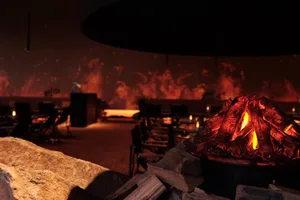 Cozy restaurant interior with a wood fireplace, stone mantle, and comfortable seating area