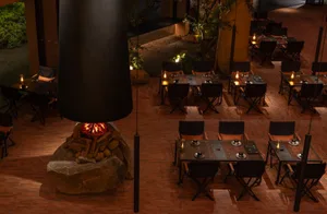 Warm and inviting dining area with multiple tables and chairs surrounding a fireplace