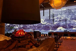溫馨餐廳內部，設有壁爐、瀑布屏風、餐桌、椅子與盆栽