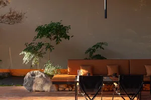 Modern living space with two couches, a dining table, chairs, and potted plants, featuring wooden elements and a neutral color scheme