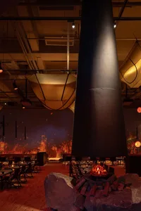 Modern dining space with a central black cylindrical structure, multiple chairs, and dining tables, creating a unique and inviting atmosphere