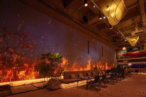 A modern restaurant interior with a large fireplace, comfortable seating, and a dining table, creating a warm and inviting atmosphere