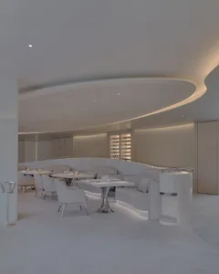 Elegant restaurant interior with white chairs and tables, modern design, clean lines, and warm lighting