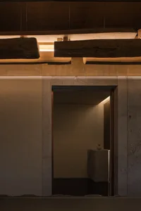 A modern bathroom with two sinks, stone walls, and a doorway leading to another room