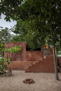 A serene outdoor area with a staircase, potted plants, and a bench, surrounded by natural scenery