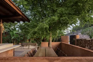 A wooden dining table with a bench and chairs in a cozy patio area, perfect for gatherings and social events