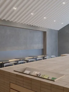 Cozy cafe interior with a counter and chairs, featuring a display of books and a warm atmosphere