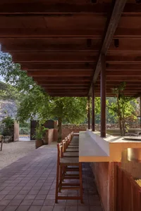 A modern kitchen with a wooden countertop island surrounded by metal chairs, well-lit with natural or artificial light
