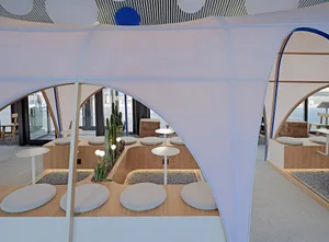 A cozy outdoor dining space with a white tent, cushioned chairs, and potted plants, creating a warm and inviting atmosphere