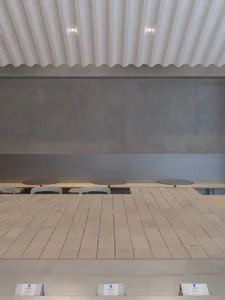 A calm and inviting restaurant with a long wooden dining table surrounded by white chairs and a bench