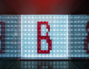 A modern art gallery with a large red sculpture lit by neon lights, surrounded by glass walls and metal accents