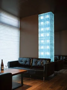 Contemporary living space with a black leather couch, wooden table, and a large glass wall with a blue tint, featuring two chairs and a sophisticated design