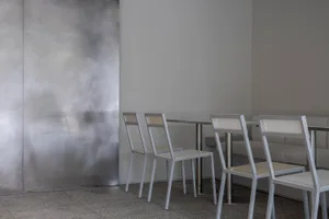 A modern dining area with white chairs and tables arranged around a central dining table, creating a comfortable seating arrangement for guests