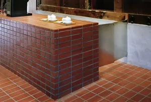 A brick wall in a kitchen area with a sink and two cups, featuring a warm and rustic atmosphere