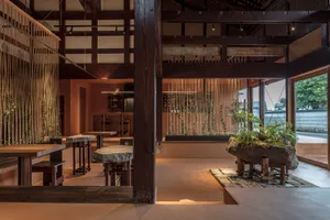Modern dining space with wooden walls, tables, chairs, and potted plants, creating a warm and inviting atmosphere