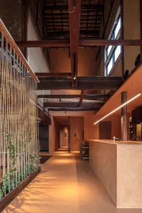 Warm restaurant interior with a wooden bar, stone walls, and a cozy atmosphere, featuring two chairs and a counter