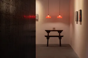 Empty room with a wooden bench and two hanging lights, white walls, and a clean and bright atmosphere