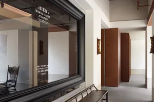 Interior view of a building with a wooden bench in front of a glass door, surrounded by chairs in a comfortable and inviting space