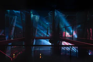 A bustling indoor space with a large red structure in the center, surrounded by people walking and engaging in various activities