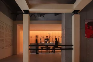 A lively restaurant and bar space with wooden dining table and bench, multiple bottles on display, and cups placed around the room