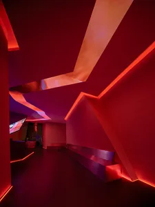 A modern living space with bold red walls, a white ceiling, a bench, and a mounted TV, creating a stylish and inviting atmosphere
