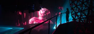 An indoor event venue with a large screen displaying a futuristic robot character, set up for a performance or presentation with a modern, high-tech atmosphere