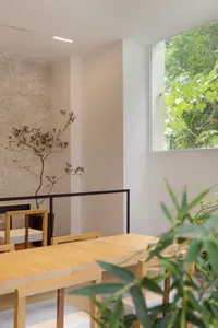 Warm dining area with a wooden table, potted plants, and natural light from a window