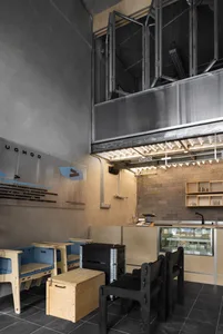 A modern kitchen with wooden floors and walls, featuring multiple dining tables and chairs, creating a warm and inviting atmosphere