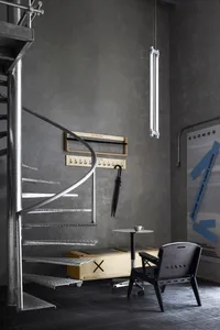 Modern living space with metal staircase, a chair, and a dining table in a contemporary and stylish environment