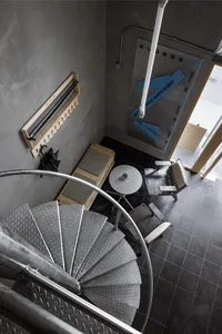 A modern staircase with a metal railing in a residential building, well-lit with possible natural and artificial light sources