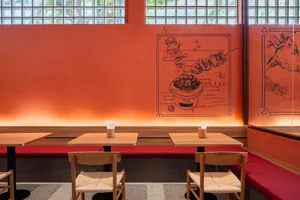 Warm and inviting Asian restaurant interior with wooden tables and chairs, a bowl on one table, and a cozy atmosphere