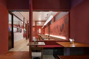 A warm and inviting Asian restaurant interior with red walls, wooden furniture, and tables set with food and diners