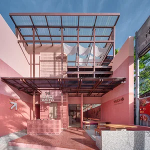 Modern restaurant interior with pink facade, wood, glass, and metal materials, multiple dining tables and chairs, warm and inviting atmosphere