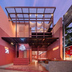 An inviting outdoor restaurant with red brick walls, dining tables, and chairs, well-lit by natural light and overhead lighting