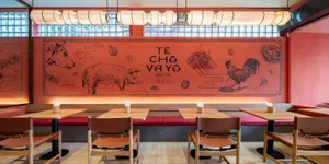 A modern dining area with red walls, wooden tables, and chairs, creating a warm atmosphere