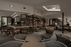 Inviting restaurant interior with tables, chairs, potted plants, and a warm atmosphere