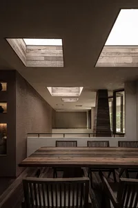 Open modern living space with a wooden dining table, chairs, and a kitchen area with a sink and cabinets
