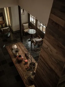 Cozy living space with wooden floors and walls, featuring a dining table, chairs, and decorative vase