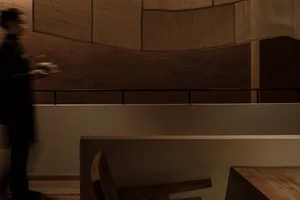 A calm and inviting restaurant dining area with two chairs and a person standing near one of them, surrounded by warm and cozy atmosphere
