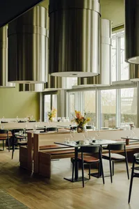 Warm and inviting restaurant interior with wooden floors, tables, chairs, and decorative elements, featuring multiple dining tables and comfortable seating