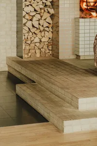 Cozy living area with a brick fireplace, stone mantle, and a stack of wood, featuring a warm and inviting atmosphere