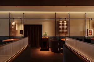 A modern restaurant dining area with tables, chairs, potted plants, artwork on the walls, and a stylish atmosphere