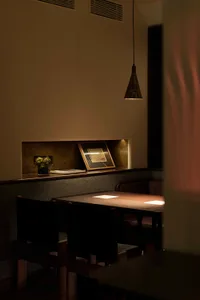 A cozy dining area with a wooden table surrounded by chairs, a book, and a vase, perfect for a meal or conversation