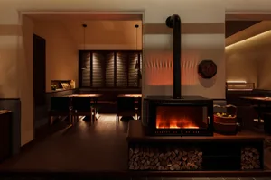 Cozy restaurant dining area with a wood stove, multiple chairs, and dining tables near the fireplace